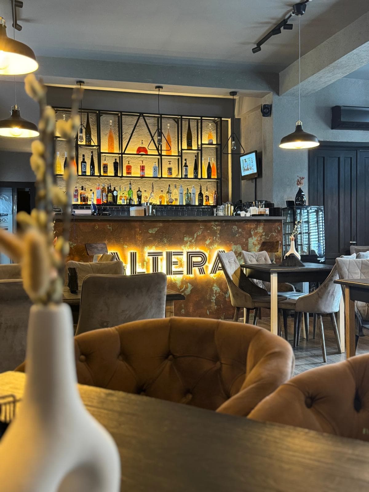 Interiorul Altera: barul cu sigla luminată și fotolii tapițate