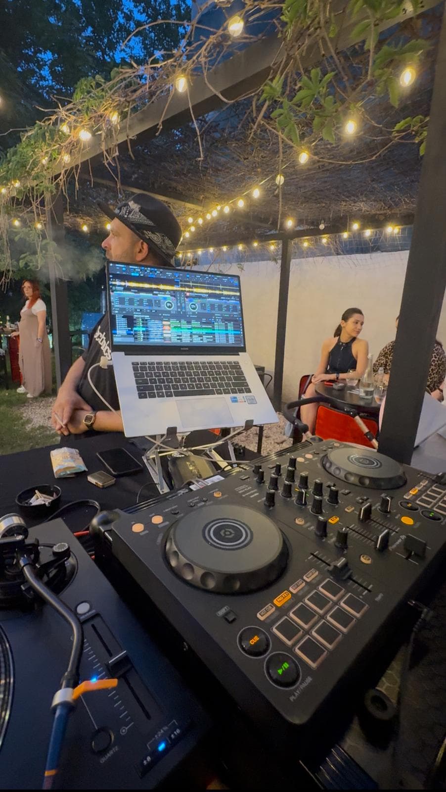 DJ la pupitru sub ghirlandele din grădina Altera, în timpul unei seri
